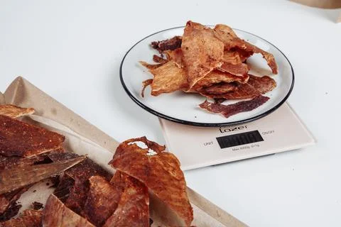 A guy puts dried meat in paper boxes in black gloves Stock Photos