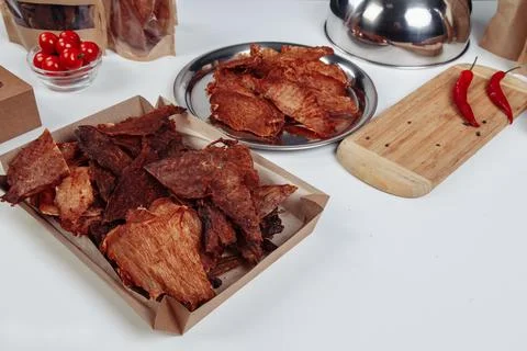 A guy puts dried meat in paper boxes in black gloves Stock Photos