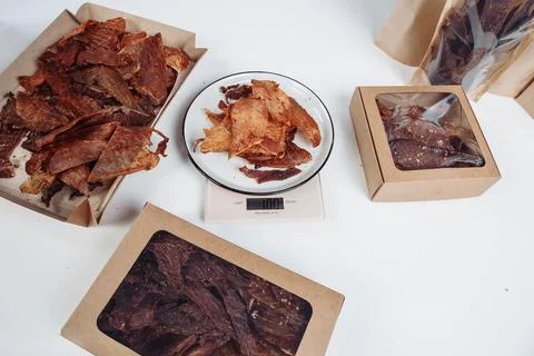 A guy puts dried meat in paper boxes in black gloves Stock Photos