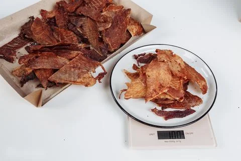 A guy puts dried meat in paper boxes in black gloves Stock Photos