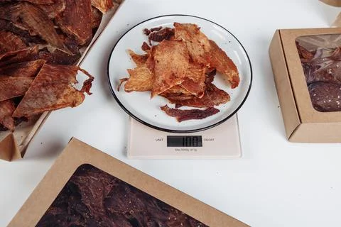 A guy puts dried meat in paper boxes in black gloves Stock Photos