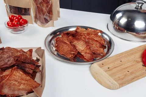 A guy puts dried meat in paper boxes in black gloves Stock Photos