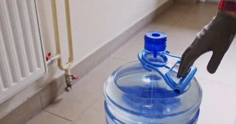Guy puts handle on water bottle lifting container off floor Stockbeeldmateriaal 294598630