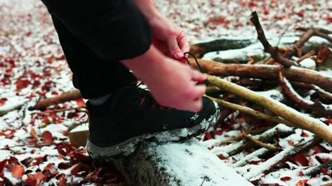 The guy puts his foot in the shoe on a snow-covered log and ties his shoelaces. Stock Footage 299857891