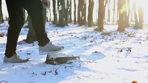 The guy puts his foot on a stump and tying shoelaces in sneakers at sunset Stockbeeldmateriaal 77035883