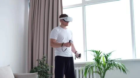 Guy puts on his head a virtual reality helmet. Handsome man wearing future Foto stock