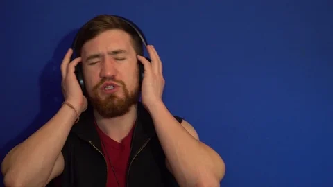 The guy puts on his headphones and starts to listen music, to sing 库存影片 124304501