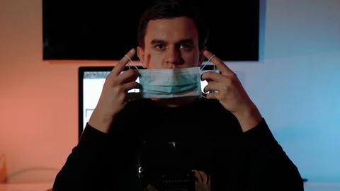 The guy puts on a mask and turns to work to the computer Stock Footage 128398054