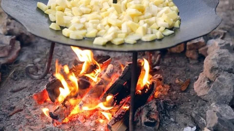 The guy puts the meat and fat in a frying pan. Potato and meat on plow disc Stock Footage 76195936