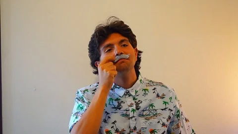 A guy puts a photo booth props moustache to celebrate movember Stock Footage 95540580