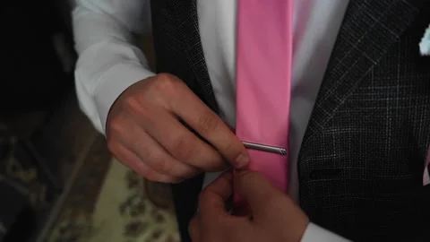 The guy puts on a pink tie and pin it to his shirt. Stock Footage 138115296