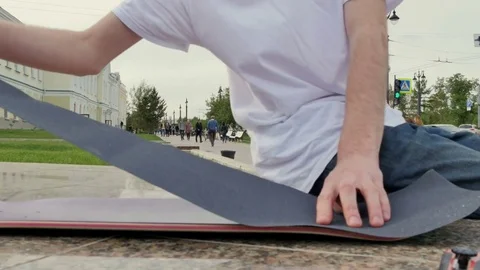 Guy puts a rough surface on the skateboard 스톡 동영상 80552959