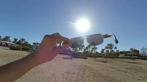 The guy puts on sunglasses on the beach Video stock 98934387
