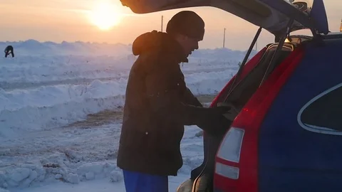 The guy puts things in the trunk of a car. the evening Twilight Vidéo 72149213