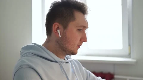 Guy puts on wireless headphones, listens to music, enjoys shaking his head Stock Footage 154686350