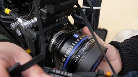 Guy putting a lens on a cinema camera Stock Footage 85560849