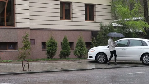 The guy quickly goes to the car under the umbrella. The rains Stock Footage 74854155