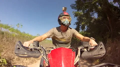Guy racing through the Thai jungle and sand on an ATV with a helmet on his head Stock Footage 45030129