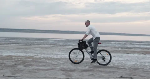 Guy raises body off seat while cycling along uneven coastal path Stock Footage 323966307