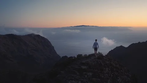 The guy raises hands up on the edge of the earth on top of the mountains above Stock-Footage 99752681