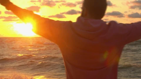 The guy raises his hands on the sea on the background of the sunrise Stock Footage