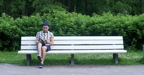 The guy is reading a book in the park. Stock Footage 52453173
