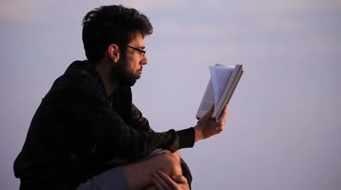 Guy reading a book on a rock Stock Footage 58117918