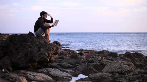 A guy reading a book on the rock  Stock Footage 58118504