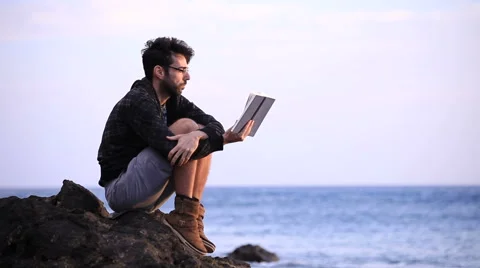 A guy reading a book on the rock  Stock Footage 58119120