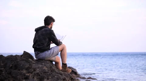 A guy reading a book on the rock  스톡 동영상 58119611