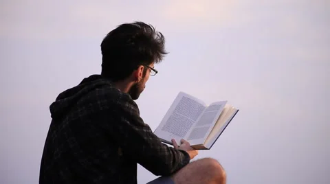 Guy reading a book on a rock 스톡 동영상 58120087