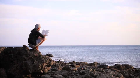 Guy reading a book on a rock Stock Footage 58121275