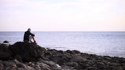 Guy reading a book on a rock Video stock 58121993
