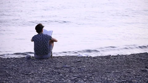 A guy reading a book sitting on beach 動画素材 58233225
