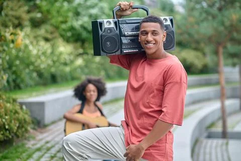 Guy with record-player on shoulder smiling aside Stock Photos