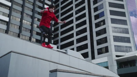 Guy in red and black clothes jumping and practicing parkour Stock Footage 264200285
