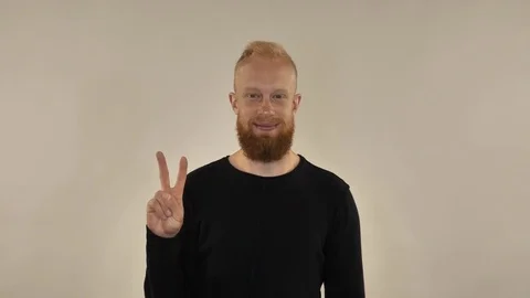 A guy with a red beard is smiling and showing a sign of victory Stock Footage 81770709
