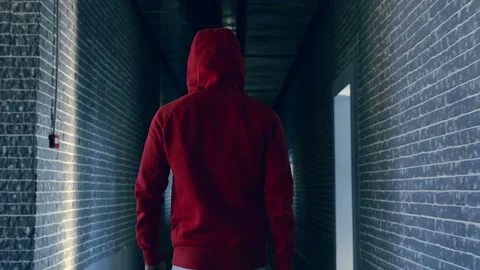 Guy in the red capuche walking in the dark hallway. Video stock 98588155