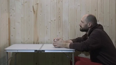 A guy in a red dress drinking tea from a white mug and looks forward to the room Stock Footage 119542785