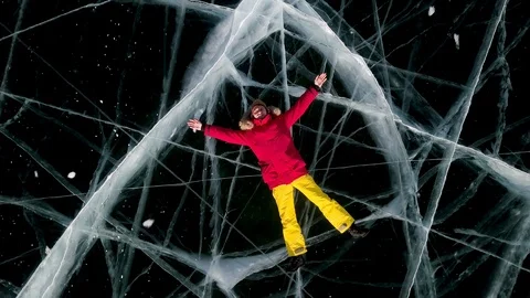The guy in the red jacket is lying on the transparent ice. Baikal, aerial view Stock Footage 113182013