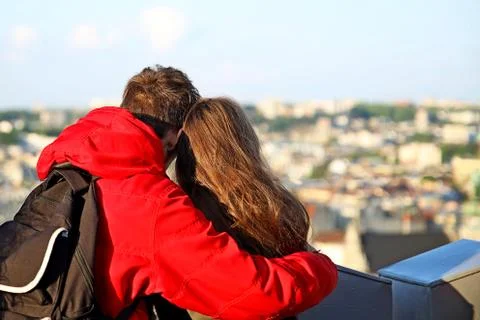 A guy in a red jacket is standing in an embrace with a long-haired girl. A yo Stock Photos