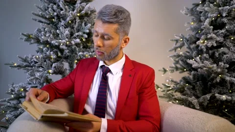 A guy in a red suit holds a book in his hands. immersed in an interesting story. Video stock 167650516