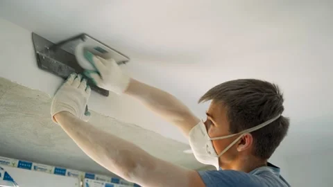 The guy in the respirator is grinding the ceiling after puttingtying. Stock Footage 151792704