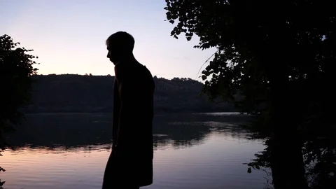 The guy rests on the river bank, sits on a chair and looks at the river Stock Footage 114631319