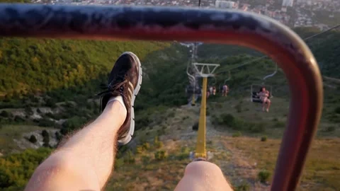 The guy rides the cable car and shakes his legs with a view of the sea and the c Stock-Footage 150580623