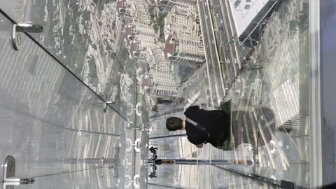 A guy rides a glass slide on a skyscraper in downtown Dubai Stock Footage 238542582