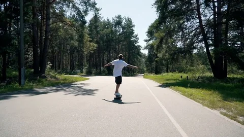 A guy rides a skateboard on an empty road Stock Footage 99678421