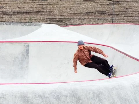 The guy rides a skateboard on the steep side of the rollerdrome Stock Photos