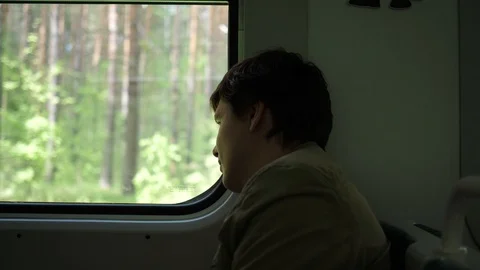 The guy rides the train and looks out the window, watching the moving objects Vidéo 110915354