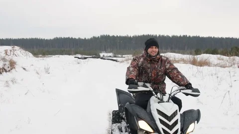 The guy is riding an ATV on a snow-covered road in winter Stock Footage 84954385